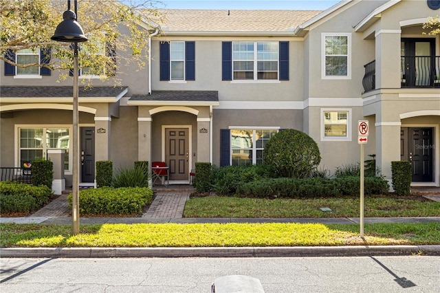 multi unit property featuring a shingled roof and stucco siding