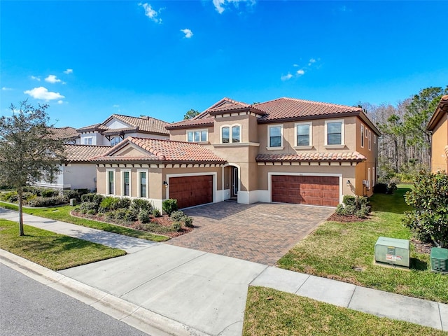 mediterranean / spanish house featuring stucco siding, a front lawn, a tile roof, decorative driveway, and a garage