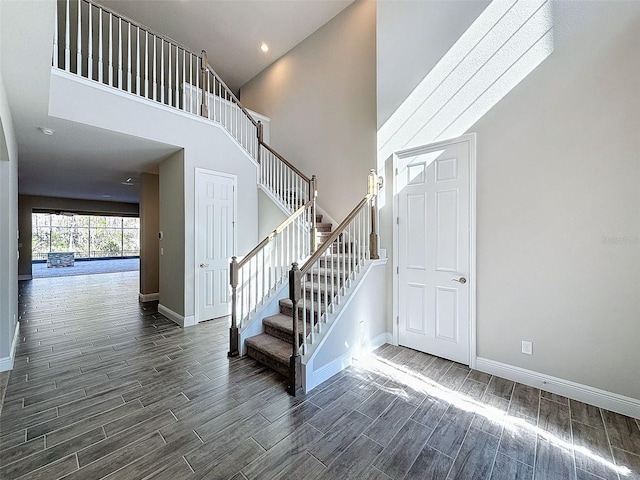 stairs with recessed lighting, baseboards, a high ceiling, and wood finish floors