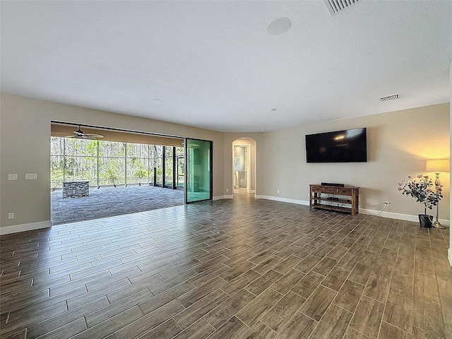 unfurnished living room with visible vents, arched walkways, baseboards, and wood tiled floor