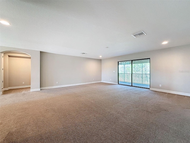 unfurnished room with baseboards, visible vents, recessed lighting, arched walkways, and light colored carpet