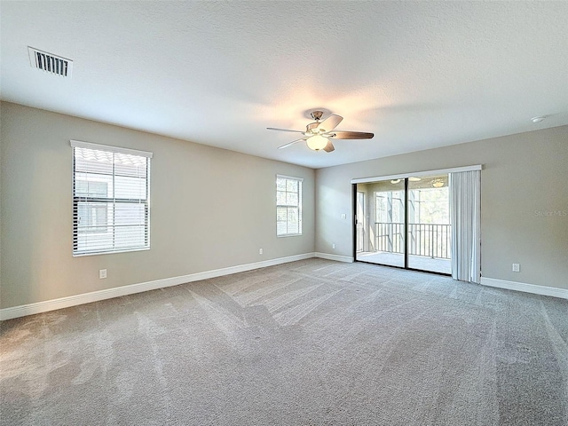 empty room featuring ceiling fan, light carpet, and a textured ceiling