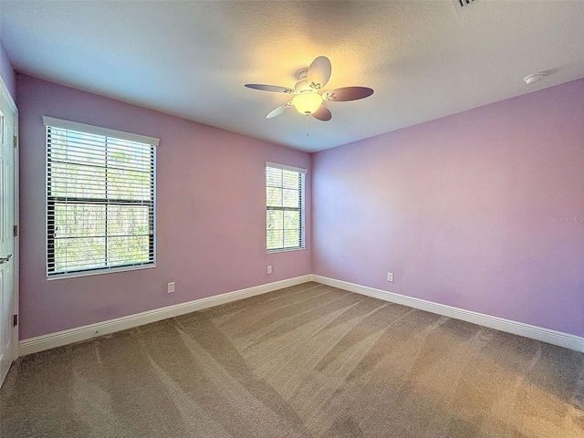 carpeted spare room featuring a textured ceiling, a ceiling fan, and baseboards