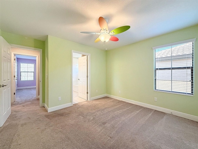 unfurnished bedroom with ceiling fan, baseboards, ensuite bathroom, and light carpet