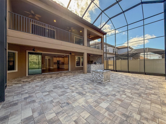 view of patio / terrace featuring ceiling fan, an outdoor kitchen, a lanai, and a balcony