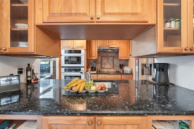kitchen featuring dark stone countertops, double oven, decorative backsplash, and sink