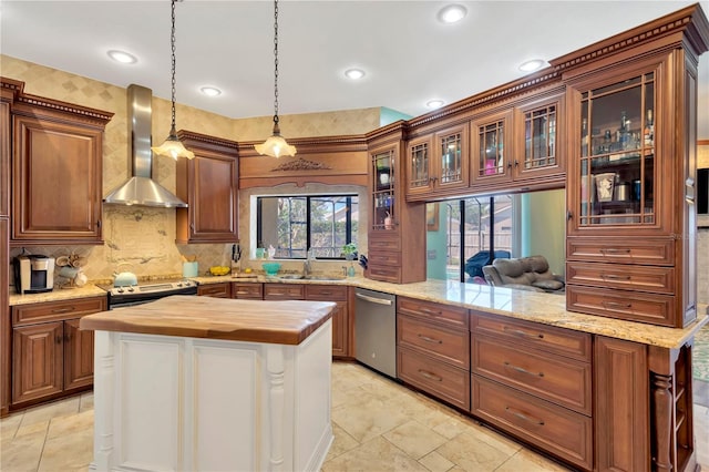 kitchen featuring butcher block countertops, stainless steel appliances, decorative light fixtures, kitchen peninsula, and wall chimney exhaust hood