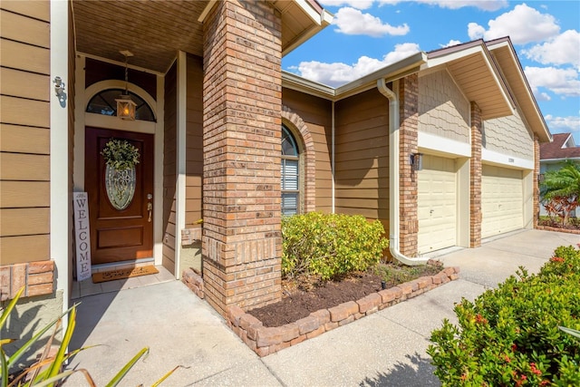 entrance to property with brick siding, concrete driveway, and a garage