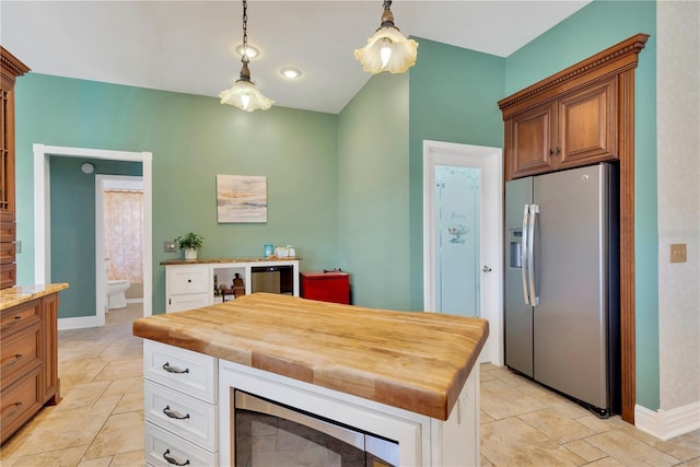 kitchen featuring wooden counters, a center island, appliances with stainless steel finishes, pendant lighting, and white cabinets