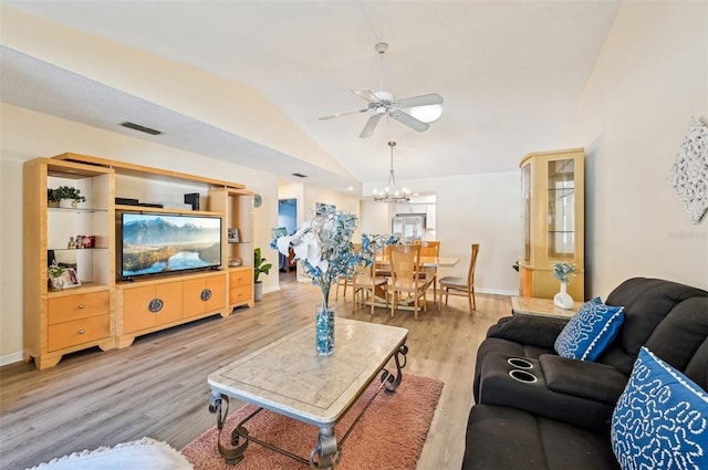 living room featuring ceiling fan with notable chandelier, vaulted ceiling, and hardwood / wood-style floors