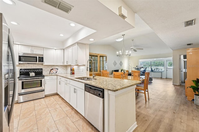 kitchen featuring sink, light stone counters, appliances with stainless steel finishes, kitchen peninsula, and white cabinets