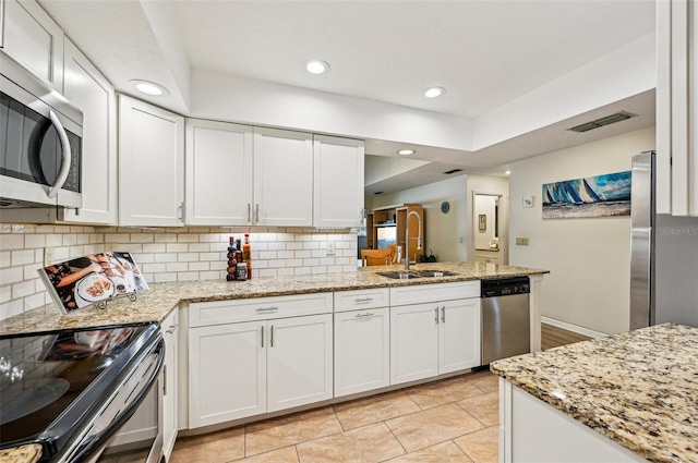 kitchen featuring sink, white cabinetry, light stone counters, stainless steel appliances, and backsplash