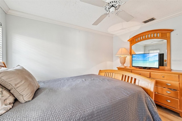 bedroom with crown molding, a textured ceiling, and light wood-type flooring