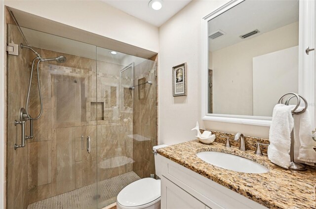 bathroom with walk in shower, vanity, and toilet