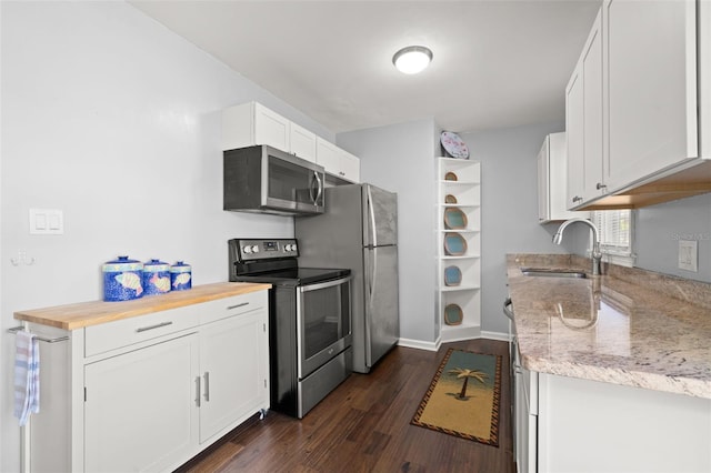 kitchen with dark wood-type flooring, appliances with stainless steel finishes, and white cabinets