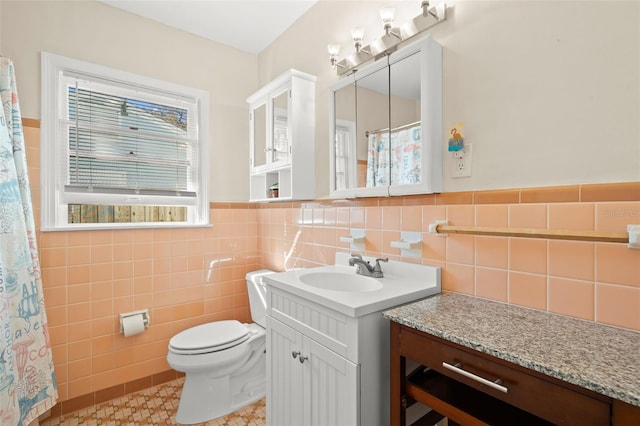 bathroom featuring vanity, toilet, and tile walls