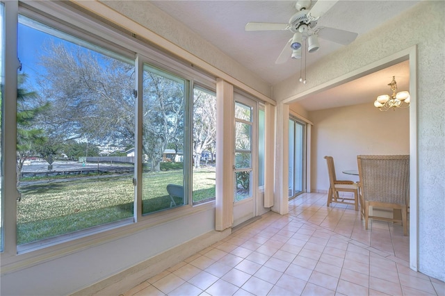 unfurnished sunroom featuring ceiling fan with notable chandelier