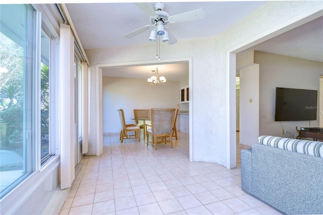 living room with light tile patterned flooring, ceiling fan with notable chandelier, and a textured ceiling