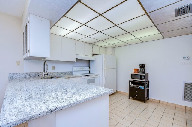 kitchen featuring sink, white appliances, a paneled ceiling, white cabinetry, and light tile patterned flooring