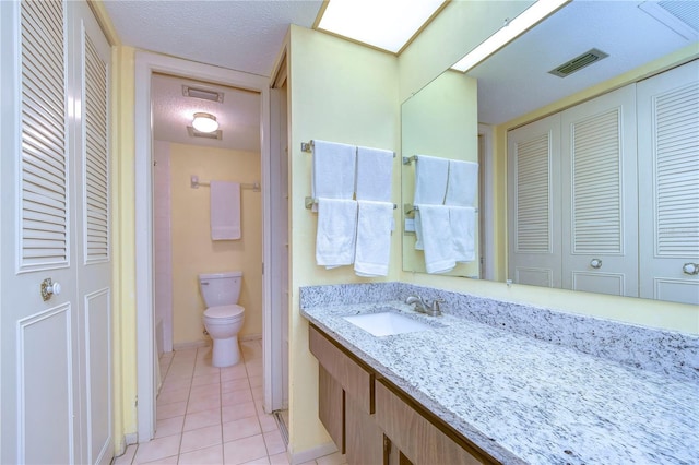 bathroom with tile patterned floors, toilet, vanity, and a textured ceiling