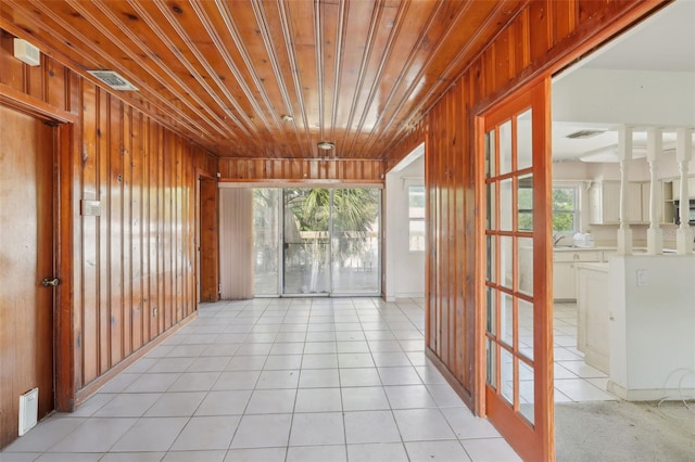 corridor with light tile patterned floors, wood ceiling, and wood walls