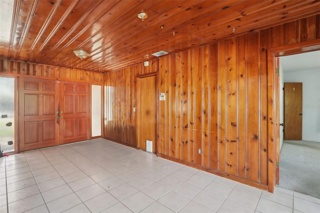 tiled empty room featuring wood ceiling and wooden walls