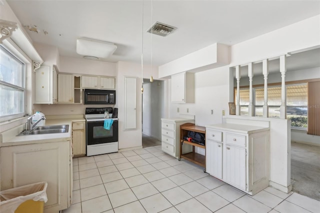 kitchen featuring electric stove, light tile patterned flooring, sink, and pendant lighting