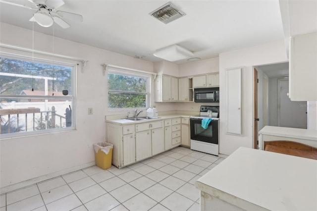 kitchen featuring light tile patterned flooring, sink, range with electric cooktop, ceiling fan, and cream cabinets