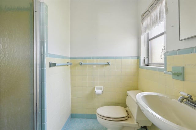 bathroom featuring toilet, sink, tile walls, and walk in shower