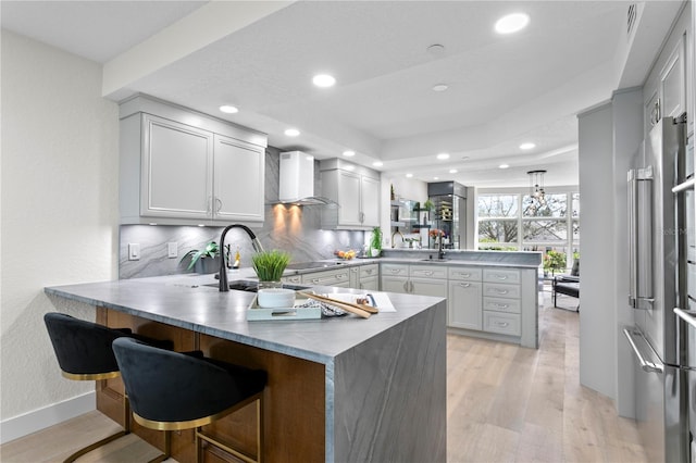 4951 Bacopa Ln S Unit 103, Saint Petersburg, FL 33715 - kitchen featuring a breakfast bar, wall chimney exhaust hood, kitchen peninsula, and light hardwood / wood-style floors