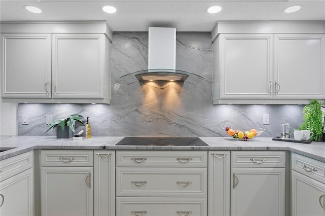 4951 Bacopa Ln S Unit 103, Saint Petersburg, FL 33715 - kitchen with black electric cooktop, tasteful backsplash, range hood, and white cabinets