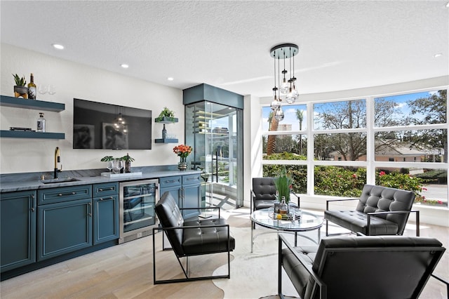 4951 Bacopa Ln S Unit 103, Saint Petersburg, FL 33715 - kitchen with wine cooler, blue cabinetry, sink, hanging light fixtures, and a textured ceiling