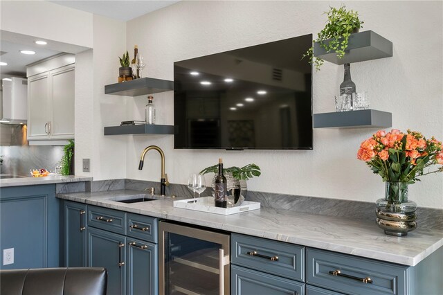 4951 Bacopa Ln S Unit 103, Saint Petersburg, FL 33715 - kitchen featuring blue cabinetry, sink, beverage cooler, light stone countertops, and wall chimney range hood