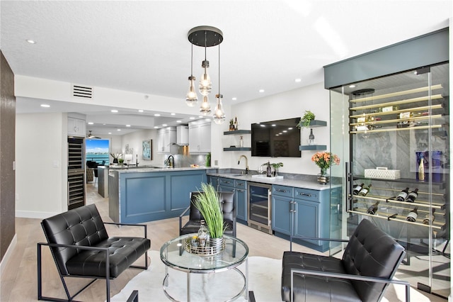 4951 Bacopa Ln S Unit 103, Saint Petersburg, FL 33715 - kitchen featuring blue cabinets, sink, kitchen peninsula, pendant lighting, and beverage cooler