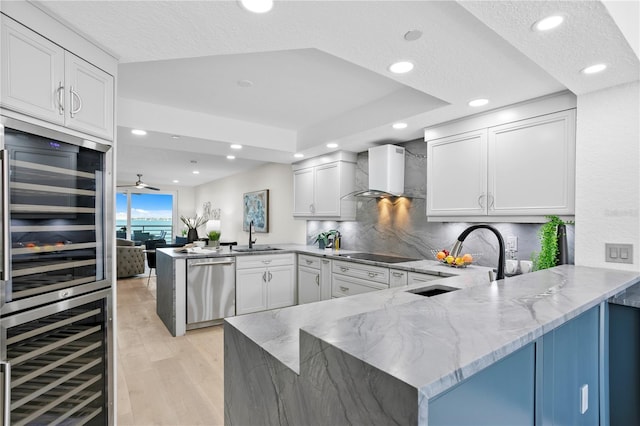 4951 Bacopa Ln S Unit 103, Saint Petersburg, FL 33715 - kitchen featuring white cabinetry, kitchen peninsula, dishwasher, and wall chimney range hood