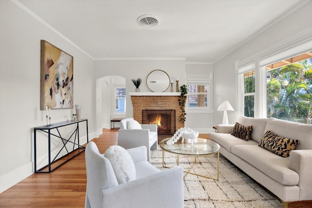 living room featuring ornamental molding, a brick fireplace, and hardwood / wood-style floors