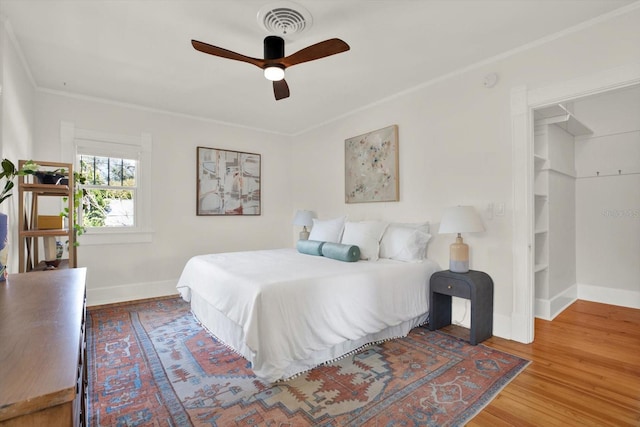 bedroom with hardwood / wood-style floors, ornamental molding, and ceiling fan