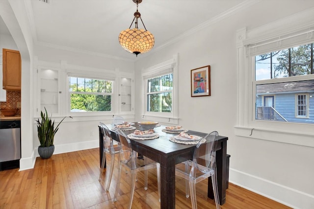 dining space featuring a wealth of natural light, ornamental molding, and light wood-type flooring