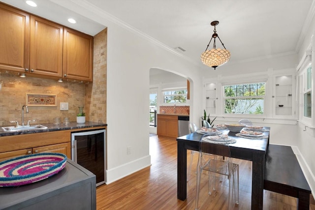 interior space featuring wine cooler, sink, hanging light fixtures, light hardwood / wood-style flooring, and dishwasher