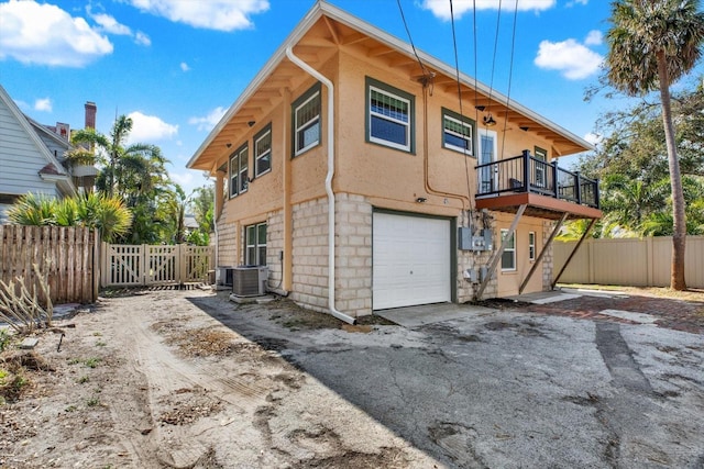 rear view of house featuring central AC, a balcony, and a garage