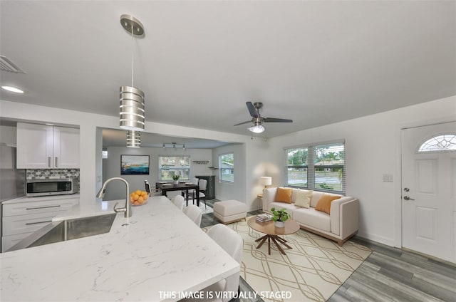 kitchen with sink, backsplash, stainless steel appliances, white cabinets, and decorative light fixtures