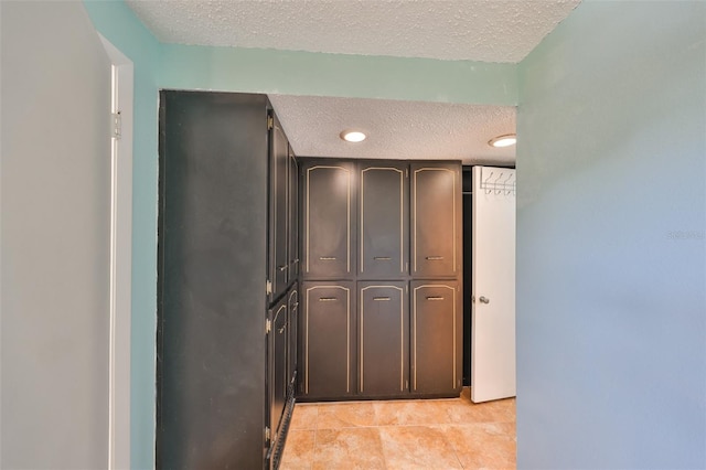 corridor featuring light tile patterned floors and a textured ceiling