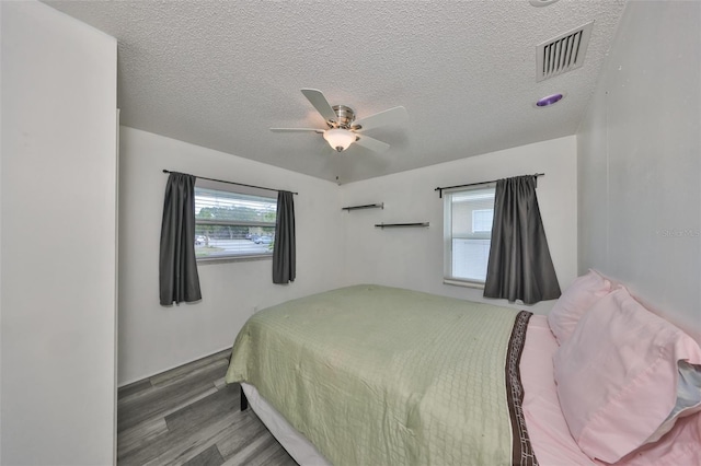 bedroom featuring multiple windows, hardwood / wood-style floors, and a textured ceiling