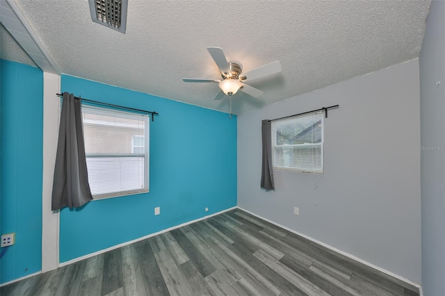 spare room featuring dark wood-type flooring, ceiling fan, and a textured ceiling