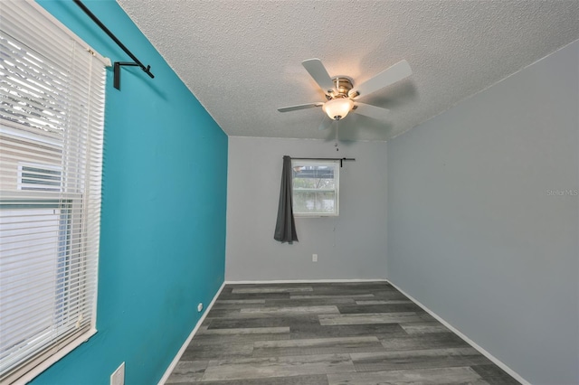 empty room featuring ceiling fan, dark wood-type flooring, and a textured ceiling