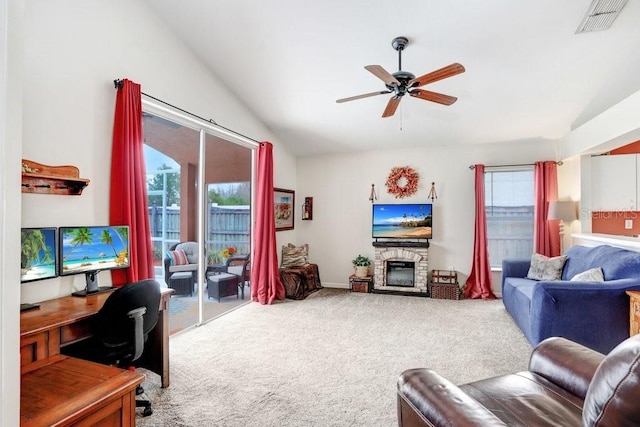 carpeted living area with vaulted ceiling, ceiling fan, a fireplace, and visible vents