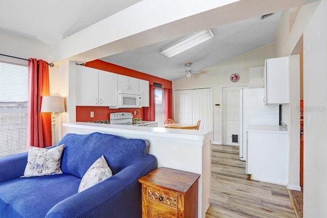 kitchen with white appliances, light wood-style flooring, a peninsula, vaulted ceiling, and white cabinetry