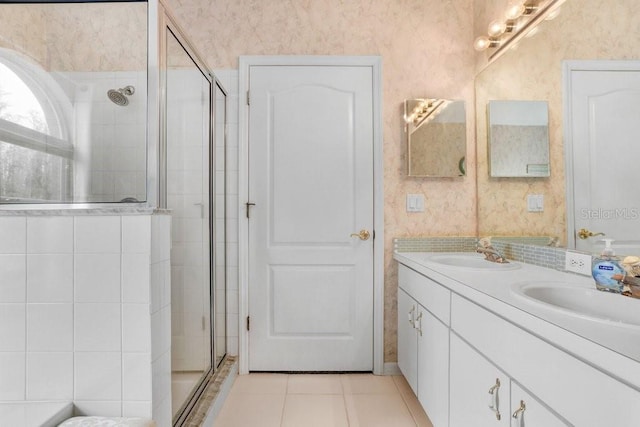 bathroom with a sink, a shower stall, and wallpapered walls