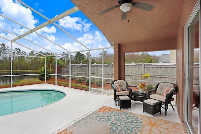 view of pool with ceiling fan, a lanai, a water view, fence, and a patio area