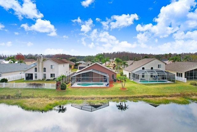 rear view of property featuring a lanai, a residential view, fence, and a yard